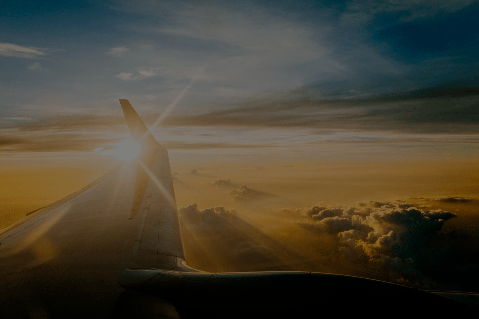 Asa de um avião sobrevoando as nuvens ao pôr do sol