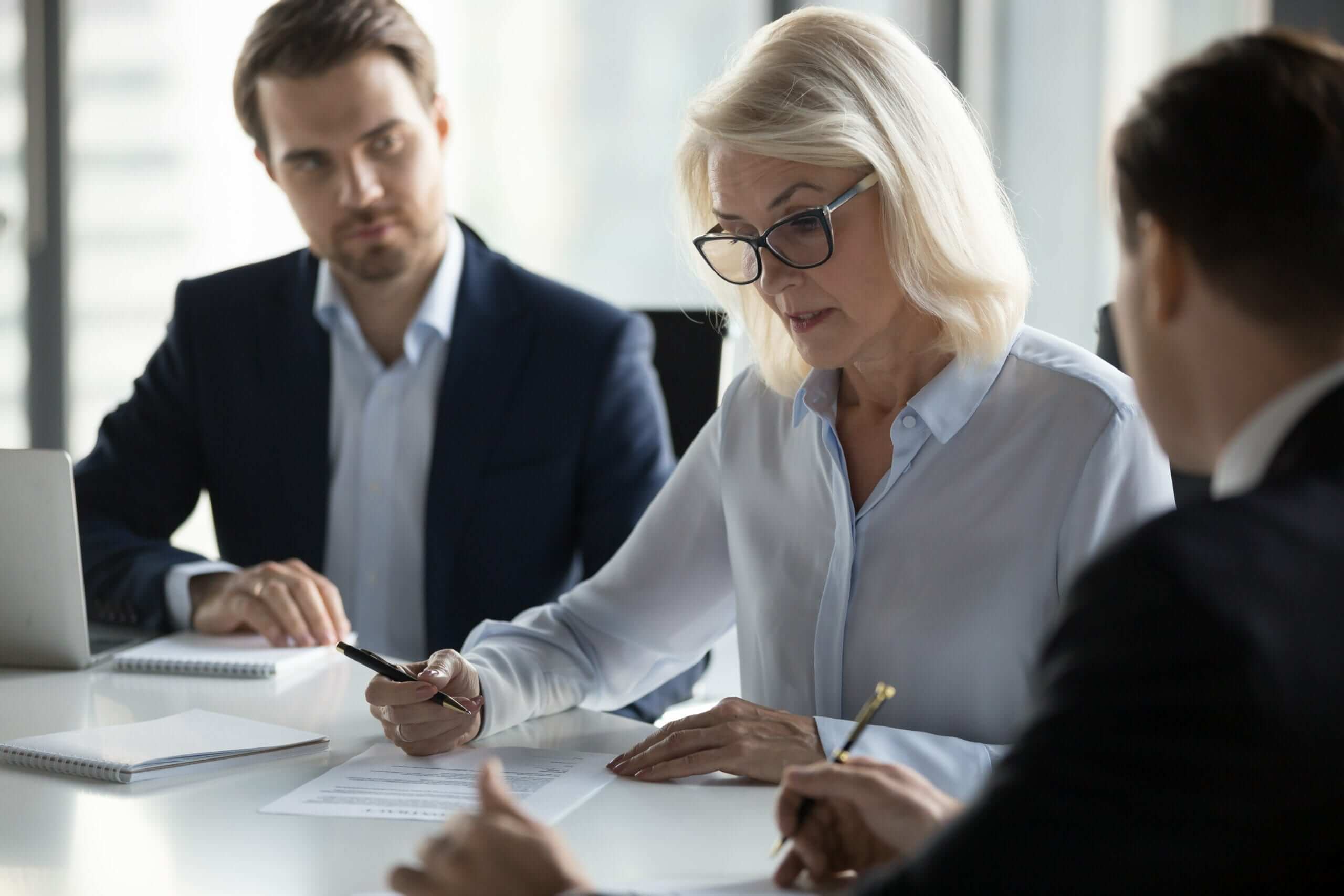 Direito empresarial societário - três pessoas em uma mesa olhando para documentos